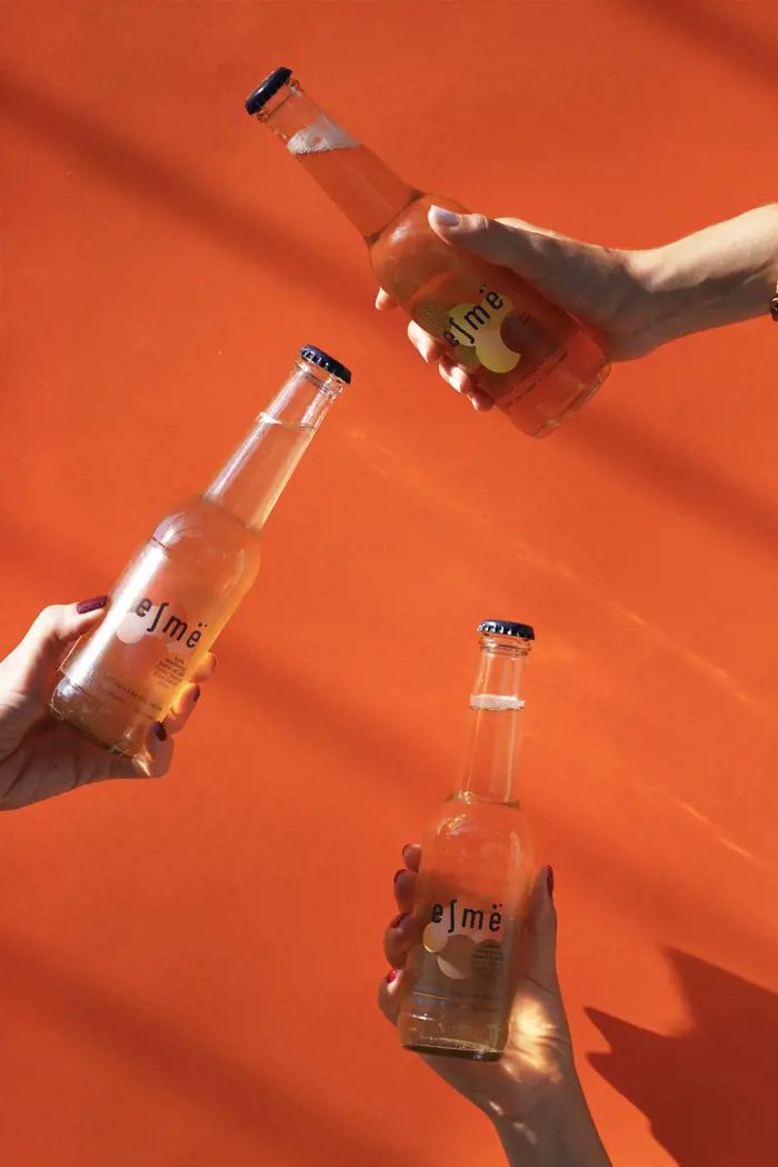 Présentation des boissons de la marque Esmë sur un fond de couleur orange sanguine
